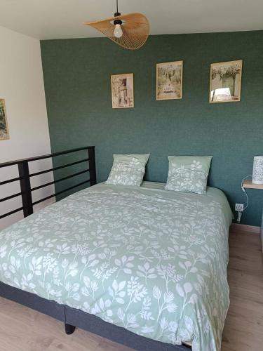 a bed in a bedroom with a green wall at Pigeonnier de campagne in Moncaut
