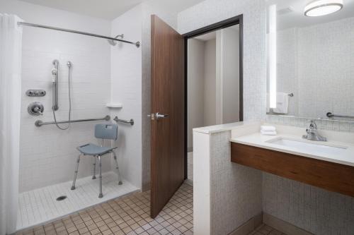 a bathroom with a sink and a shower and a chair at Holiday Inn Express & Suites Trinity by IHG in Trinity