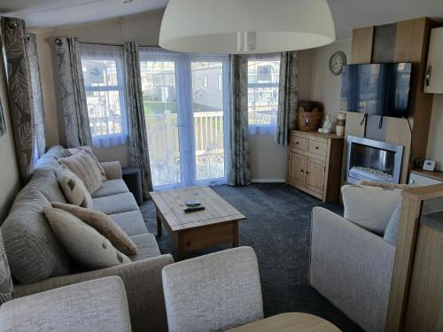 a living room with a couch and a tv at Seascape - caravan next to Fantasy Island Ingoldmells, 2 dogs max - East Coast Holidays in Ingoldmells