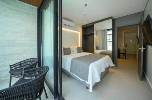 a bedroom with a bed and a balcony with two chairs at Porto2life Máximo 6 pessoas in Porto De Galinhas