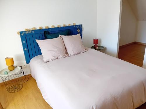 a bedroom with a large white bed with a blue headboard at Le gîte d'Elisa in Roullours