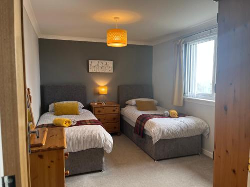 a bedroom with two beds and a window at Buaile nan Carn in Kilmuir