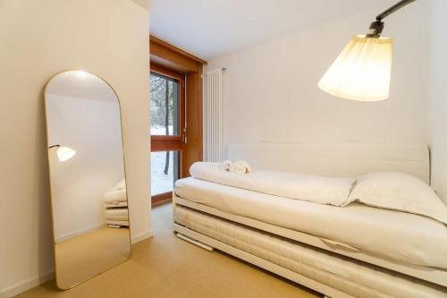 a mirror in a room with a bed and a lamp at Alpine Panorama Spacious Mountain Retreat in Crans-Montana