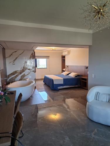 a hotel room with a tub and a bed and a bedroom at Optimum Plaza Hotel in Monte Alto