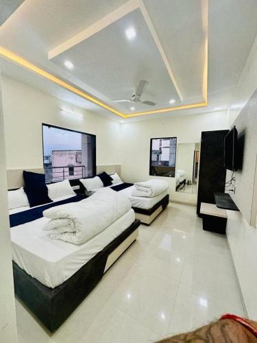 a bedroom with two beds and a flat screen tv at Hotel Pujari in Khātu