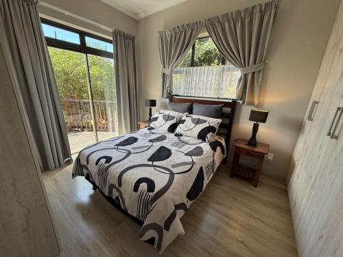 a bedroom with a bed with a black and white comforter at Hettie's Cottage in Hartenbos