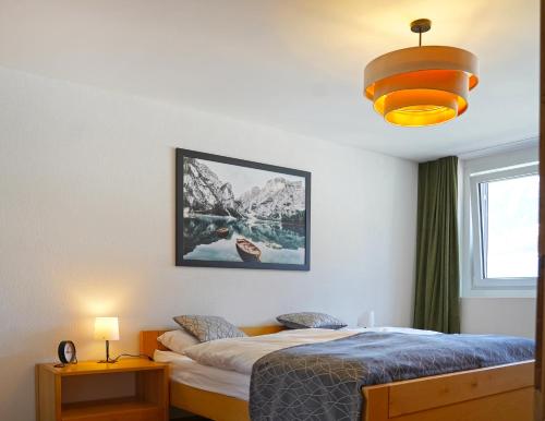 a bedroom with a bed and a lamp and a window at Penthouse mit Panoramaterrasse & Bergblick in Landquart in Landquart