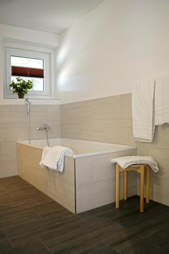a bathroom with a tub and a stool and a window at Penthouse mit Panoramaterrasse & Bergblick in Landquart in Landquart