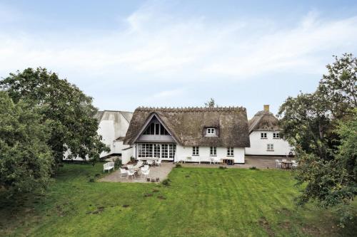 a large white house with a grass yard at By The Bay A Thatched House Lies So Beautifully in Nørre Åby