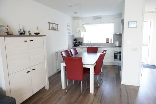 a kitchen with a white table and red chairs at Kustverhuur, Vakantiepark Fort Soleil 23 in Breskens