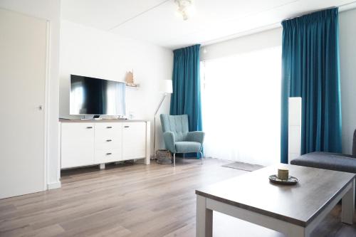 a living room with a tv and a couch and a table at Kustverhuur, Vakantiepark Fort Soleil 23 in Breskens