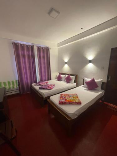 two beds in a hotel room with purple curtains at saffronvilla in Haputale