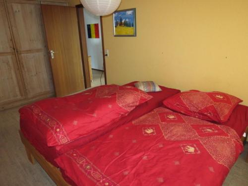 a bed with a red comforter in a bedroom at Barrierefreie Ferienwohnung Bodenseeblick in Unteruhldingen