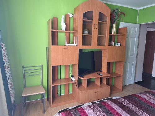 a wooden book shelf in a room with a television at Garsoniera MAIA Slănic-Moldova in Slănic-Moldova