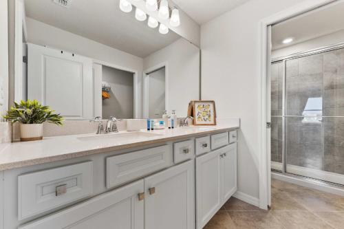 a white bathroom with two sinks and a shower at 16148 Palm Frond Ave in Orlando