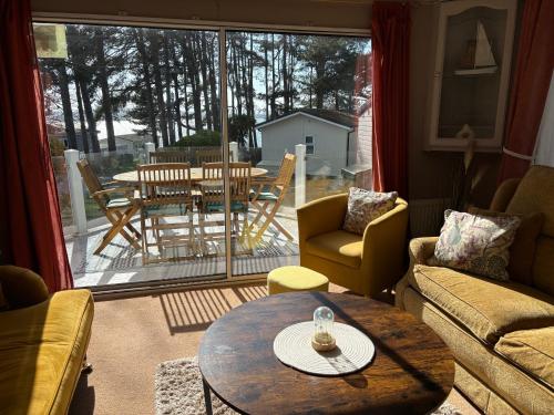 a living room with a table and chairs and a large window at Robins Lodge by the sea in Lytchett Minster