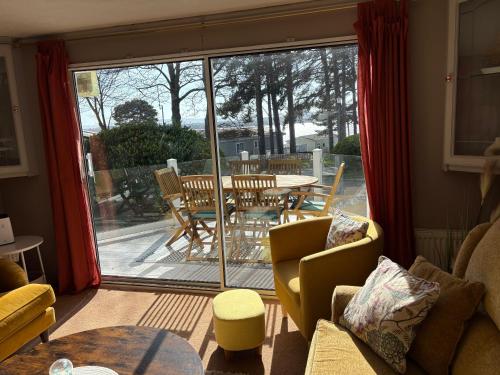 a living room with a view of a table and chairs at Robins Lodge by the sea in Lytchett Minster