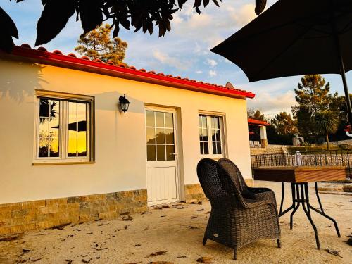 a house with two chairs and a table and an umbrella at One Bedroom Chalet with private bathroom and kitchen in Alcobaça
