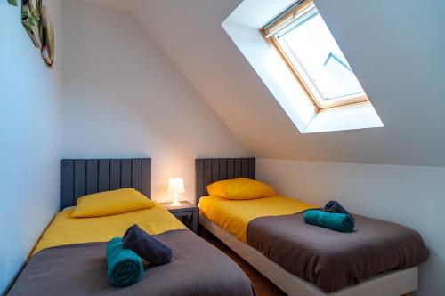two beds in a attic room with a window at Pentrez Cottage - 600m de la Plage in Saint-Nic