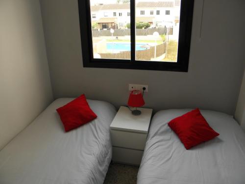two beds with red pillows in a room with a window at Apartamento en Jerez de la Frontera in Jerez de la Frontera