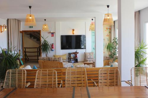 a living room with rattan chairs and a tv at Monza Surf House in Tamraght Ouzdar