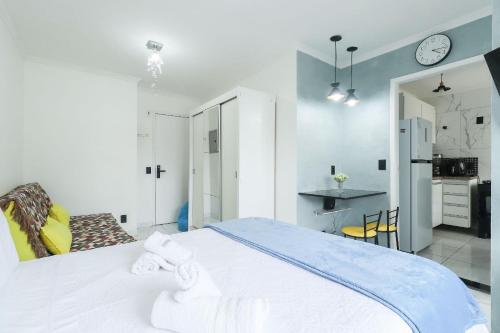 a bedroom with a large white bed and a kitchen at Condominio da Americas Maspex in São Paulo