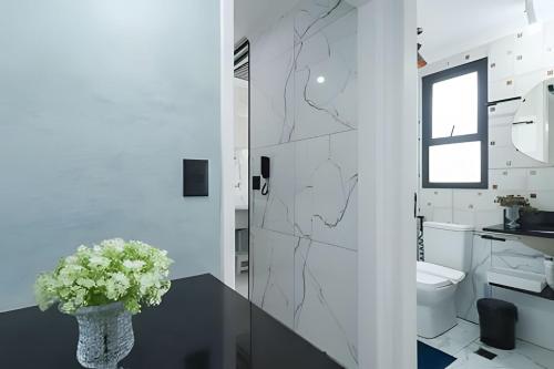 a bathroom with a toilet and a vase with flowers on a table at Condominio da Americas Maspex in São Paulo