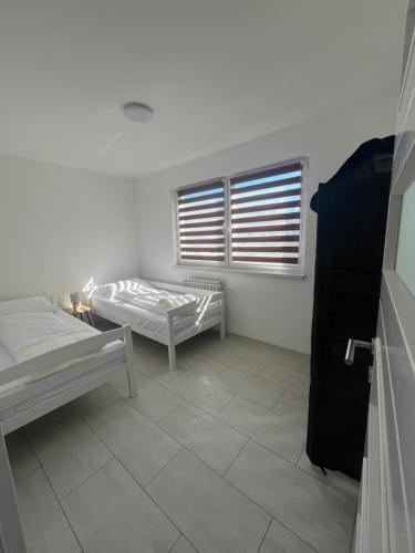 a white room with two beds and a window at Apartman Ćorić in Kiseljak