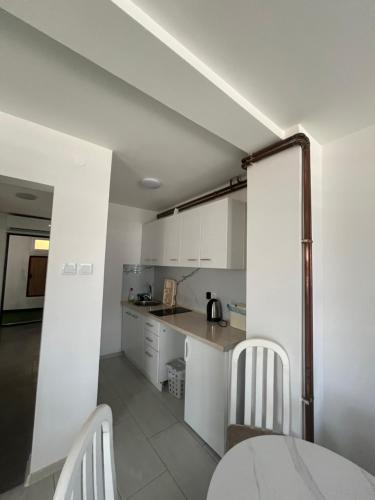 a kitchen with white cabinets and a table and chairs at Apartman Ćorić in Kiseljak