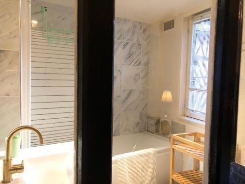 a bathroom with a bath tub and a sink at Appartement Le Notre Dame in Honfleur