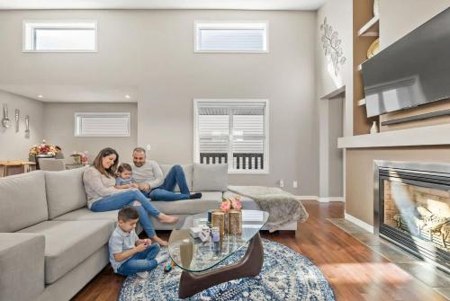 a family sitting on a couch in a living room with a fireplace at Large Family Home w Kid's Play Tent! FREE Banff Pass in Calgary