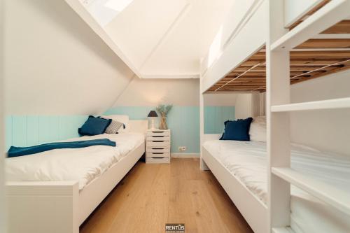 two beds in a room with white and blue walls at Villa Promenade - luxuriously apartment for 8 people in Nieuwpoort