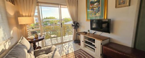a living room with a television and a balcony at Little Nest One Bedroom Apartment! in Knysna