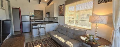 a living room with a couch and a kitchen at Little Nest One Bedroom Apartment! in Knysna