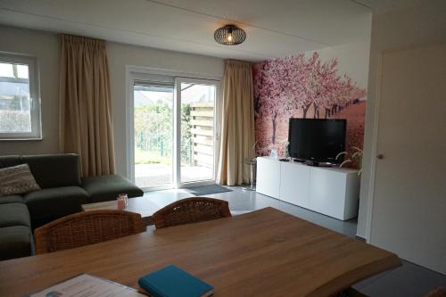 a living room with a table and a tv at Kustverhuur, Vakantiepark Fort Soleil 36 in Breskens