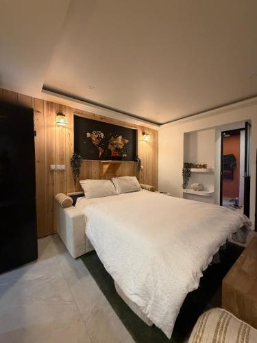 a bedroom with a large white bed and a couch at Studio chaleureux, massage, terrasse privé, barbecue et balneo in Cussac-Fort-Medoc