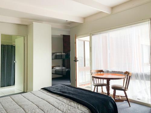 a bedroom with a bed and a table and a window at Abbotswood Motor Inn in Geelong