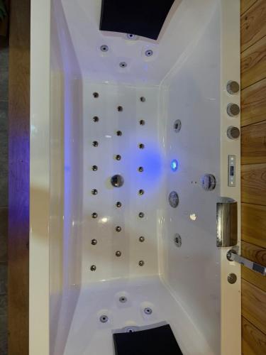 a white bathroom with a shower with buttons on the wall at Studio chaleureux, massage, terrasse privé, barbecue et balneo in Cussac-Fort-Medoc