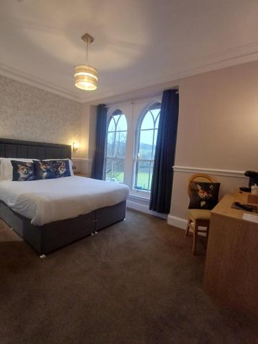a bedroom with a bed and a desk and windows at Fox and Pheasant Inn in Armathwaite