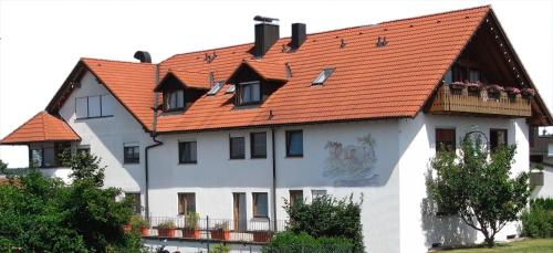 a white house with an orange roof at Landhotel Wiesenhof in Heroldstatt