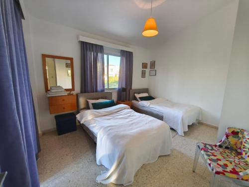 a room with two beds and a chair and a mirror at Villa Koralia in Peyia