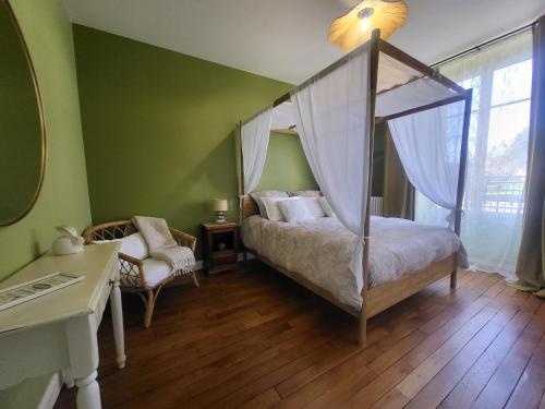 ein Schlafzimmer mit Himmelbett und Schreibtisch in der Unterkunft L'Armancine, chambres d'hôtes in Saint-Florentin