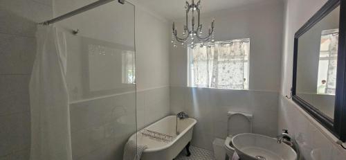 a bathroom with a sink and a bath tub and a toilet at The Lily House Hermanus - Central Private Cottages in Hermanus