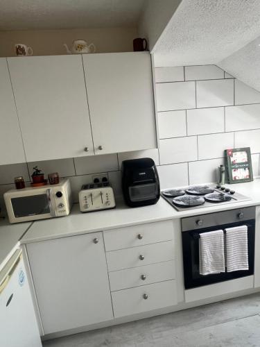 a small kitchen with a stove and a microwave at The Cosy Cumbrian Homestay in Penrith