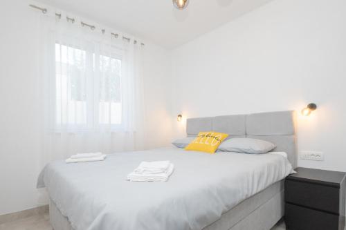 a white bedroom with a large white bed with yellow pillows at Apartman Turcic in Malinska