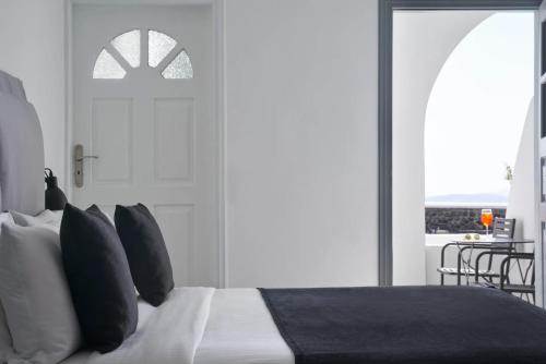 a bedroom with a bed with black and white pillows at Mr and Mrs White Oia - Santorini in Oia