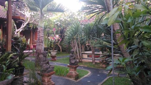 a garden with palm trees and a pathway at Suryadina Guest House in Ubud