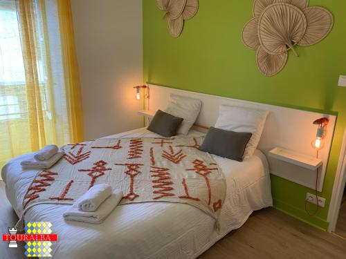 a bedroom with a large bed with a green wall at Barque Fleurie Maison Retro avec Jardin et Parking au coeur d'Aubeterre-sur-Dronne in Aubeterre-sur-Dronne