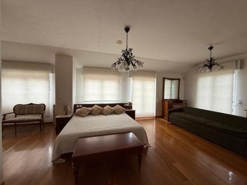 a bedroom with a bed and a couch and a chandelier at VILLA OSTRERA in Suances