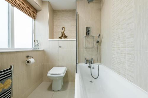a bathroom with a toilet and a tub and a sink at The Estate in Saltash